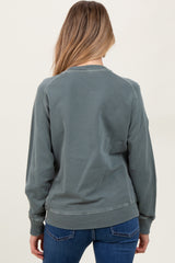 woman wearing a green maternity sweatshirt with a relaxed fit, seen from the back, paired with blue jeans
