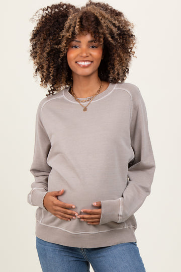 woman wearing a light gray maternity sweatshirt and holding her baby bump