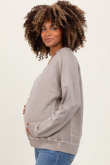 woman wearing a light gray maternity sweatshirt and holding her baby bump