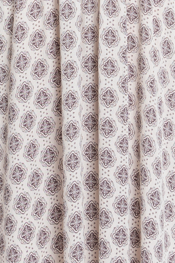 white fabric featuring a brown floral and geometric print with pleats