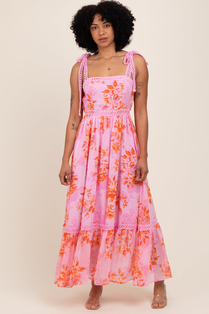 woman wearing a pink floral maxi dress with ruffled straps and a tiered skirt