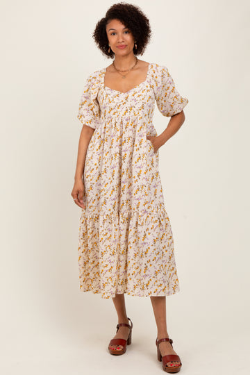 woman wearing a white floral midi dress with puff sleeves and pockets, standing against a plain background