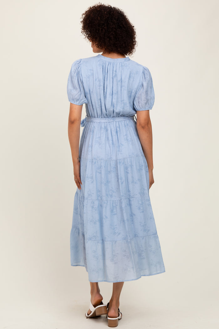 woman wearing a light blue puff sleeve midi dress with a tiered skirt and adjustable waist belt, shown from the back