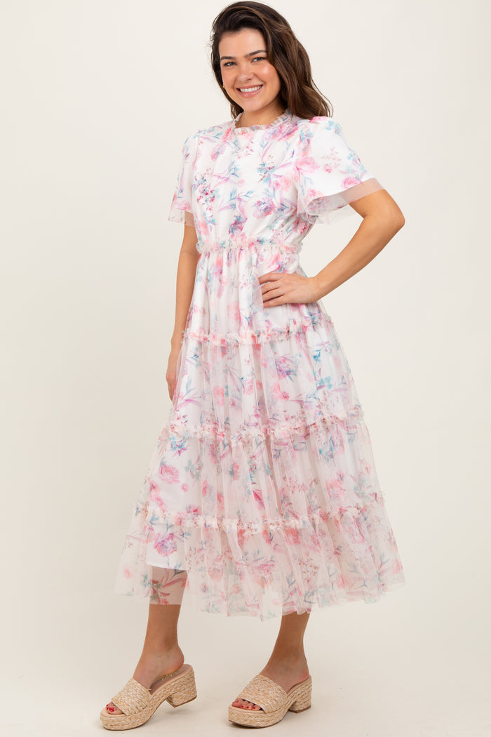 woman wearing a floral tiered midi dress with short sleeves and ruffled details, paired with tan espadrille wedges