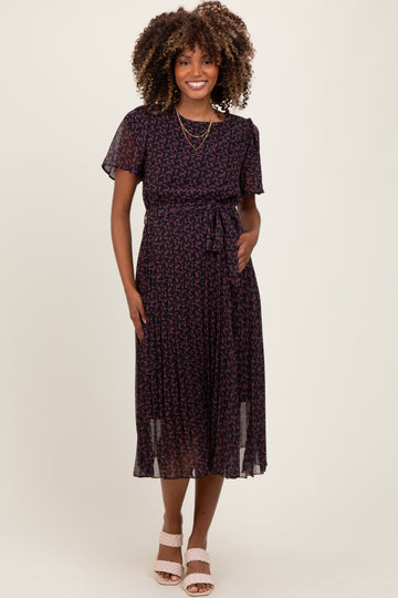 woman wearing a dark purple maternity dress with a floral pattern and a tied waist detail