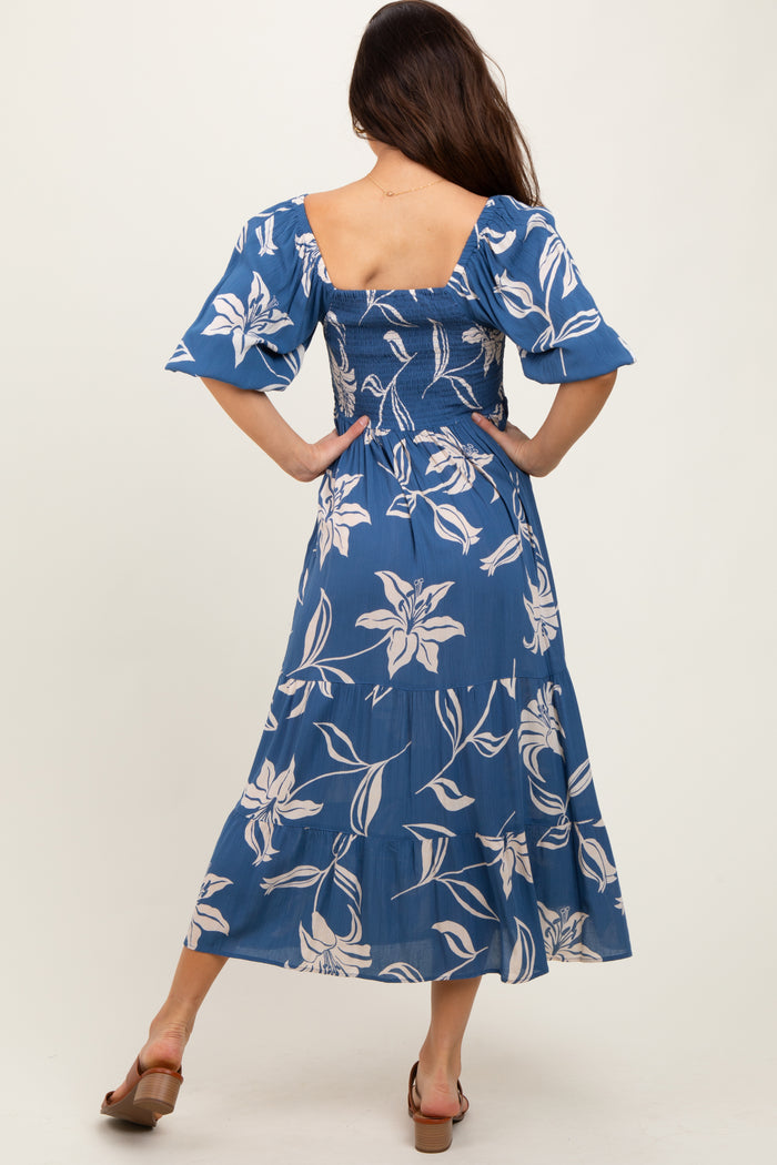 woman wearing a blue floral midi dress with short puff sleeves and a fitted smocked bodice