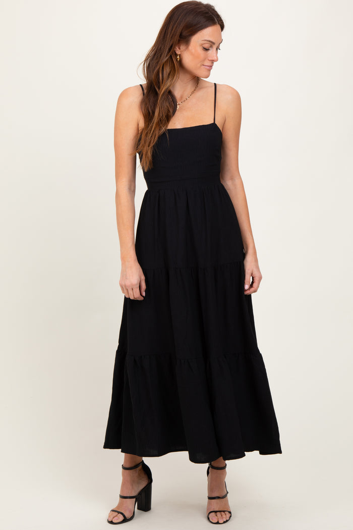 woman wearing a black tiered maxi dress with adjustable spaghetti straps and a smocked bodice