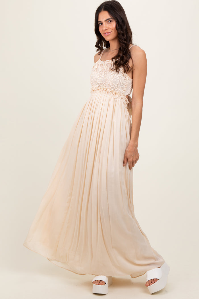 woman wearing a beige maxi dress with intricate lace detailing and a flowy skirt, standing in a relaxed pose