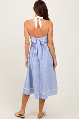 woman wearing a blue and white striped halter neck dress with a tied back detail and a midi length, shown from the back