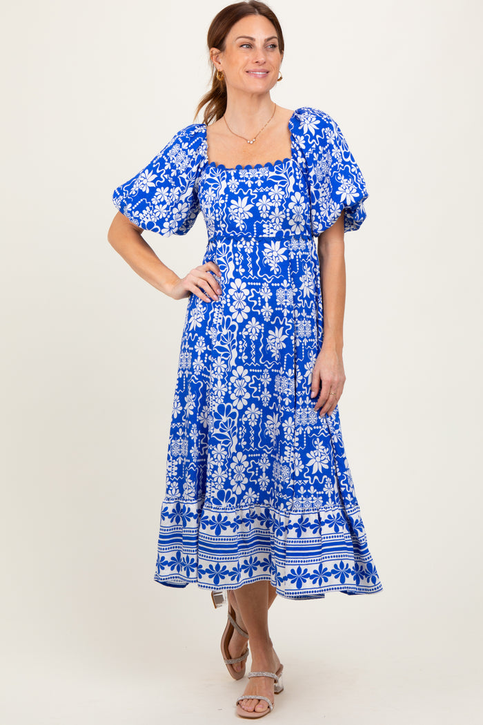 woman wearing a blue floral print puff sleeve midi dress with a square neckline and a flared skirt