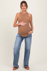 woman wearing a tan ribbed maternity tank top and blue flared jeans, holding her baby bump