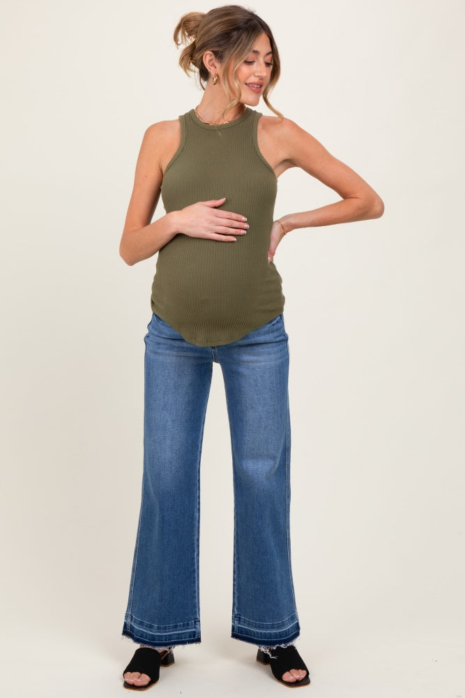woman wearing an olive green ribbed maternity tank top and blue flared jeans, highlighting her baby bump