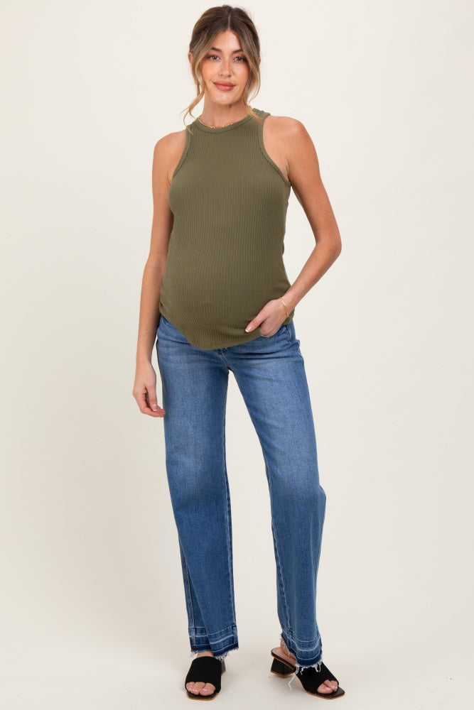 woman wearing a fitted olive green maternity sleeveless top and light blue jeans, showing her baby bump