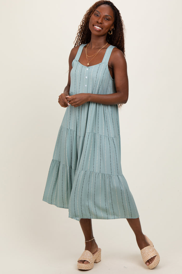 woman wearing a light blue midi dress with tiered ruffle details and buttons, standing in a relaxed pose