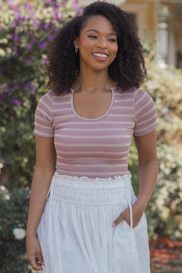 woman wearing a pink and white striped short sleeve top with a scoop neckline and white drawstring skirt