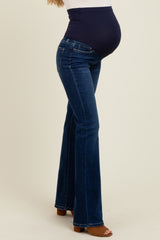 woman wearing dark blue maternity flared jeans with a belly panel, showing her baby bump