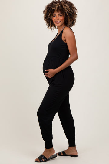 woman wearing a black sleeveless maternity jumpsuit and holding her baby bump