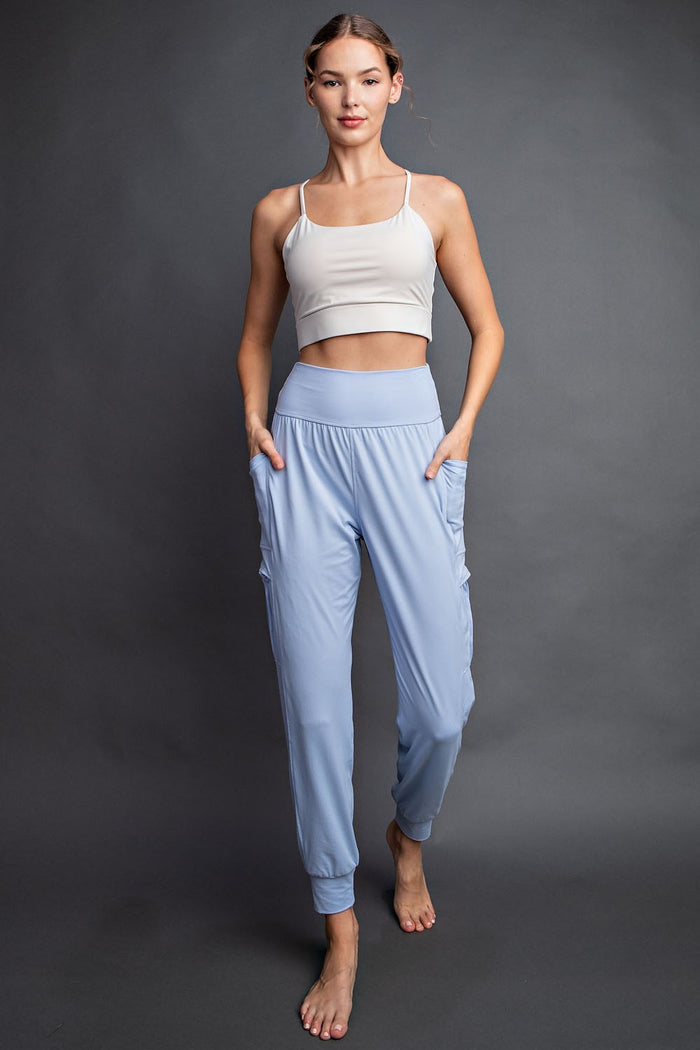 woman wearing a beige cropped tank top and light blue jogger pants with side pockets