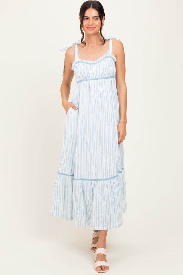 woman wearing a light blue striped maxi dress with tie straps and side pockets