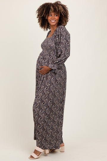 woman wearing a black floral maternity maxi dress and holding her baby bump