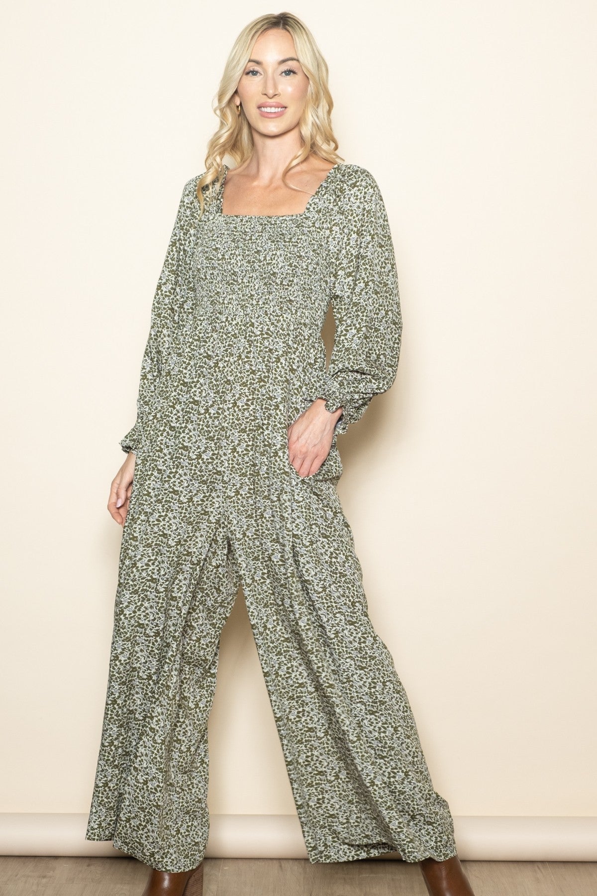 woman wearing a green floral long sleeve jumpsuit with a square neckline and wide legs