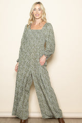 woman wearing a green floral long sleeve jumpsuit with a square neckline and wide legs