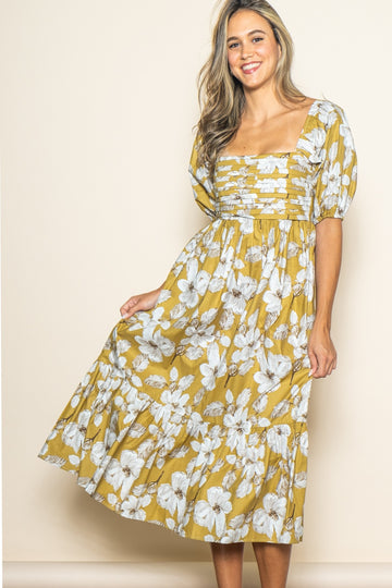 woman wearing a mustard yellow floral maxi dress with puff sleeves and tiered skirt