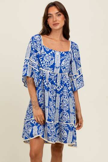 woman wearing a vibrant blue short sleeve dress with a floral print and a square neckline