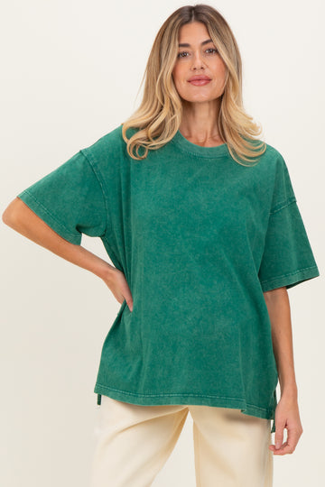 woman wearing a green oversized maternity top with short sleeves and a relaxed fit