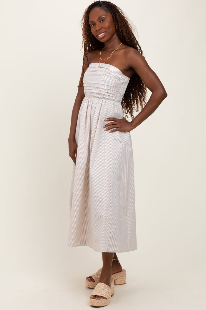 woman wearing a strapless striped midi dress with a smocked bodice and holding a pose