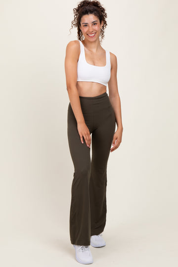 woman wearing a white cropped tank top and olive green flared leggings