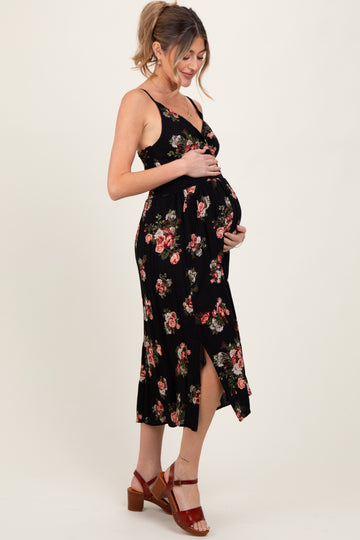 woman wearing a black floral maternity dress with a side slit, holding her baby bump