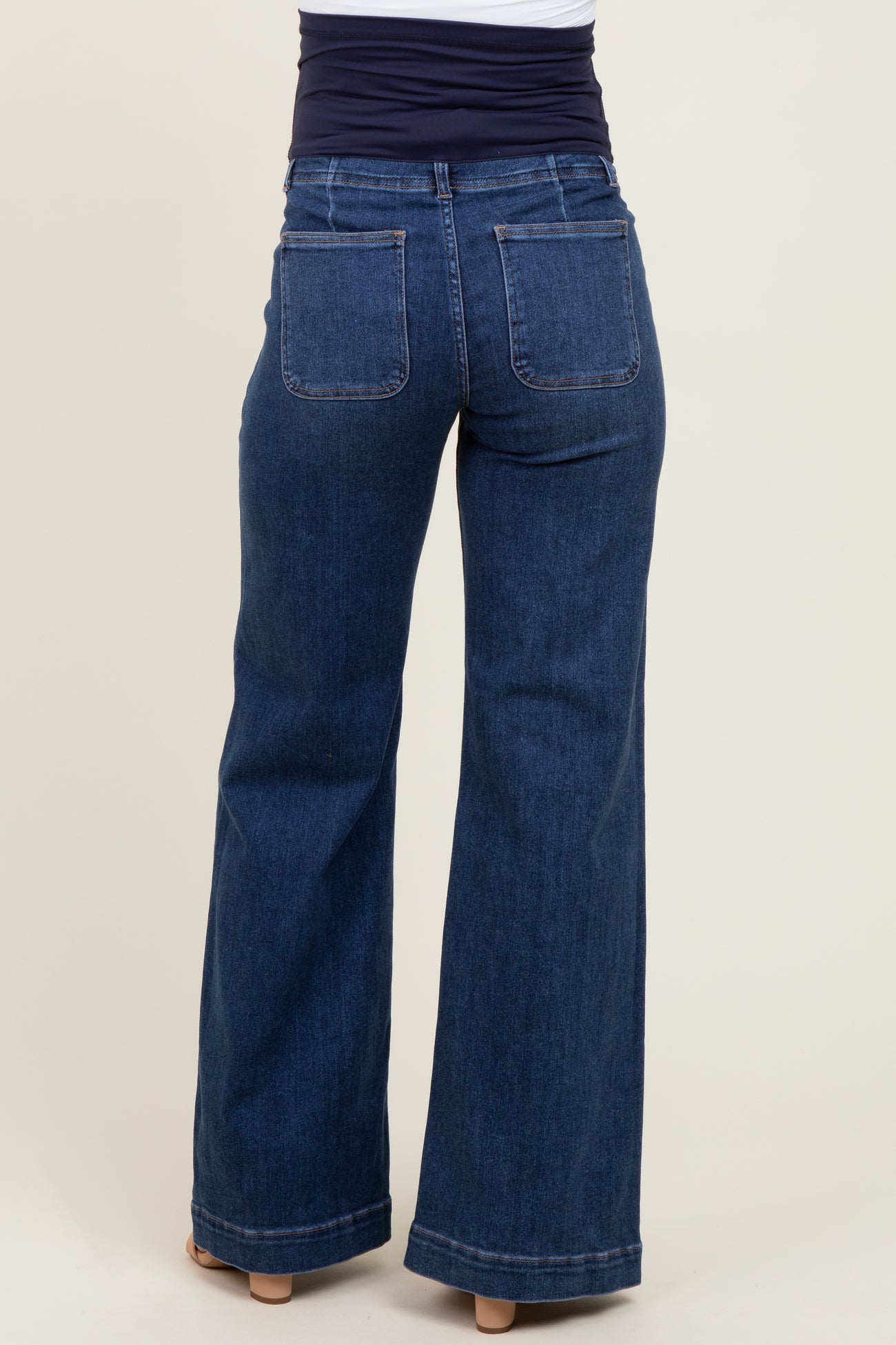 woman wearing dark blue maternity jeans with a flared leg and a stretchy waistband, viewed from the back