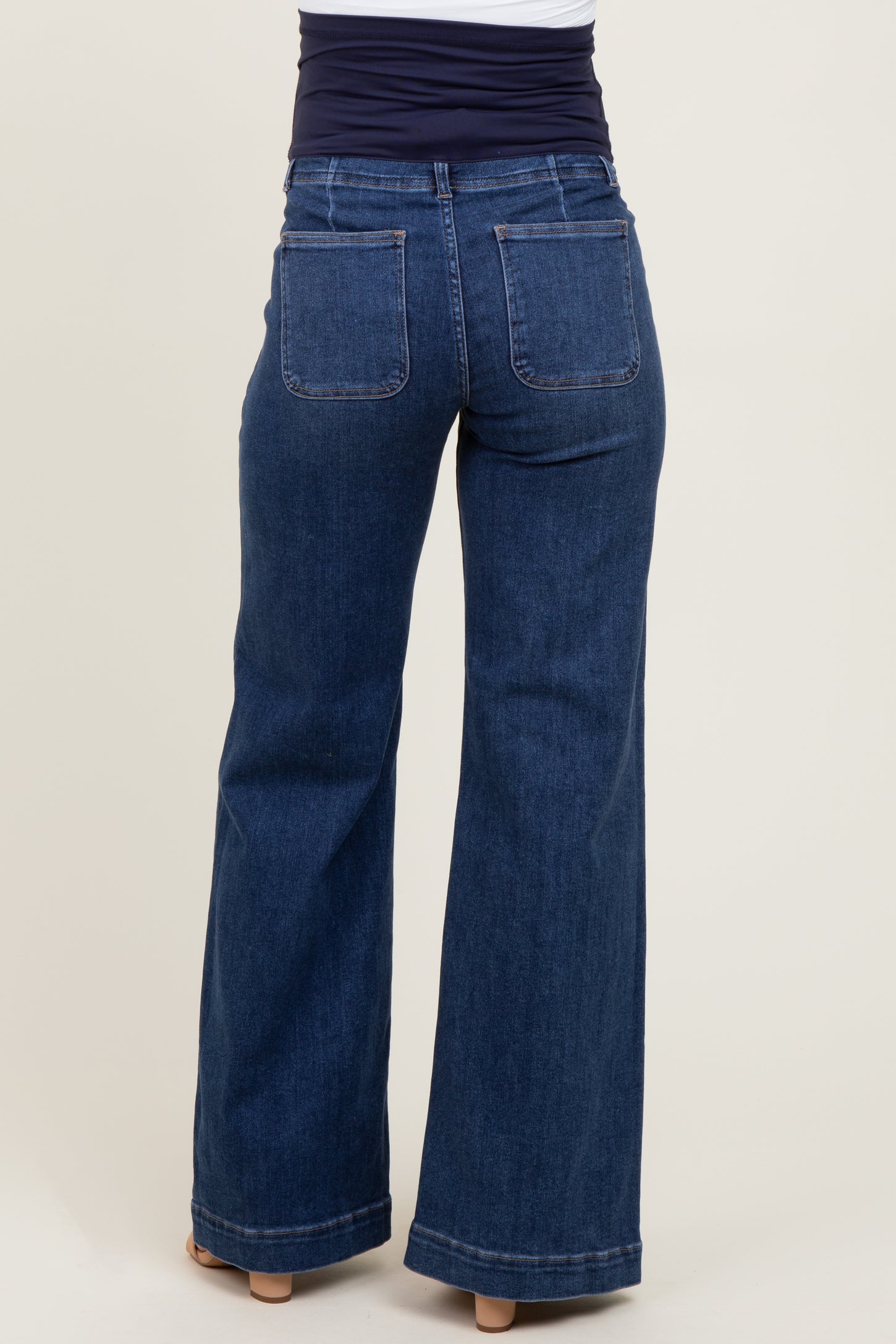 woman wearing dark blue maternity jeans with a flared leg and a stretchy waistband, viewed from the back