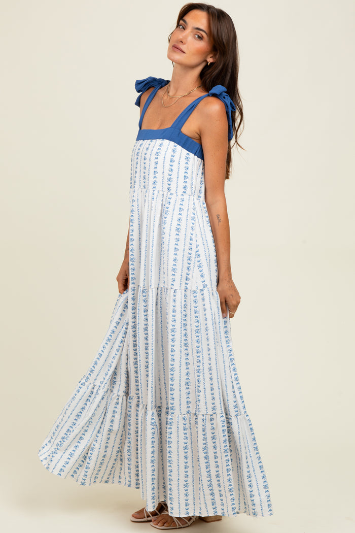 woman wearing a blue and white floral maxi dress with tie shoulder straps and a tiered skirt