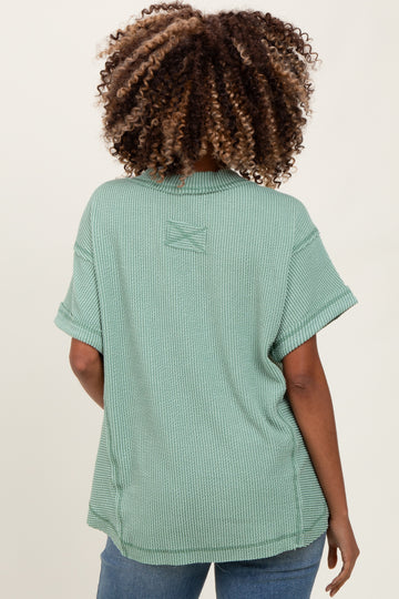 woman wearing a sage green short sleeve maternity top viewed from the back, featuring a relaxed fit and rolled sleeves
