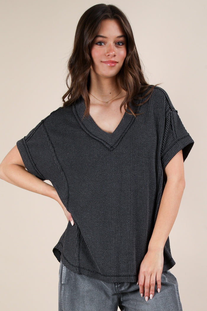 woman wearing a black ribbed v-neck oversized top and gray jeans