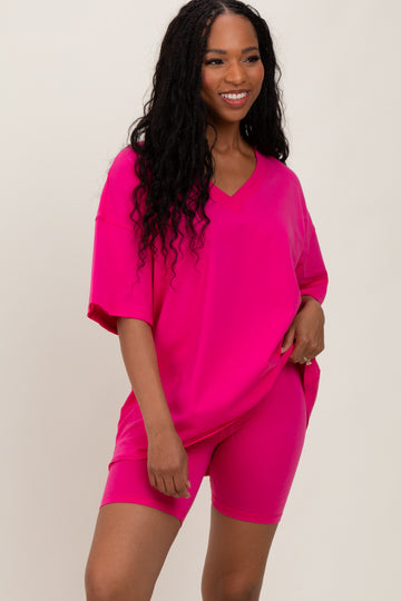 woman wearing a vibrant pink oversized t-shirt and matching shorts, smiling at the camera