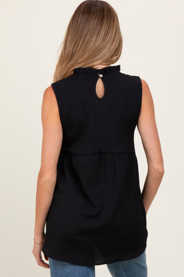 woman wearing a black sleeveless maternity top with ruffle detail and keyhole back