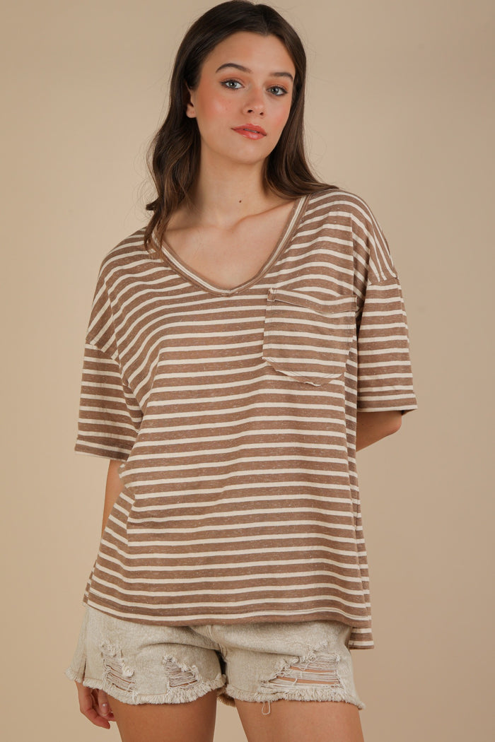 woman wearing a brown and cream striped oversized v-neck t-shirt with a front pocket and distressed white shorts