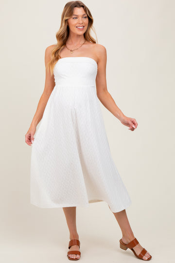 woman wearing a white strapless maternity dress with a flowy skirt and casual brown sandals