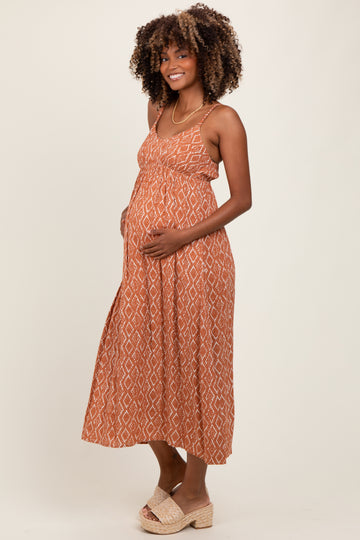 woman wearing a rust patterned maternity maxi dress and holding her baby bump