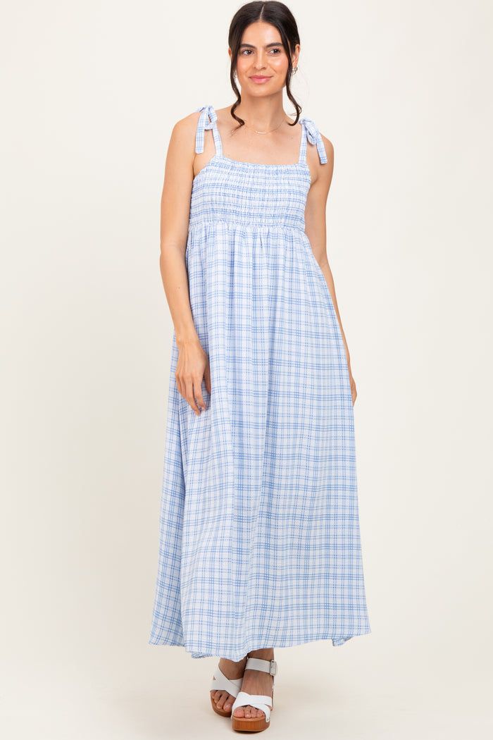 woman wearing a light blue plaid maxi dress with tie shoulder straps and a smocked bodice