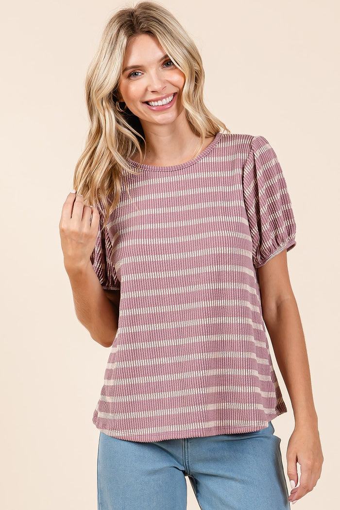 woman wearing a mauve and cream striped short sleeve top with puff sleeves, smiling and touching her hair