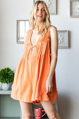woman wearing an orange sleeveless dress with a deep V-neck and tie detail, posing with a playful expression