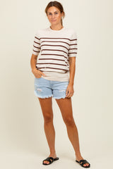 woman wearing a cream and brown striped short sleeve top and light blue distressed denim shorts