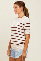 woman wearing a cream striped short sleeve sweater and denim shorts, posing sideways