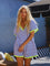 woman wearing a striped short-sleeve romper with a v-neck and neon trim, posing outside by a lounge area