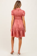 woman wearing a rose pink maternity dress with smocked bodice and ruffled hem, viewed from the back
