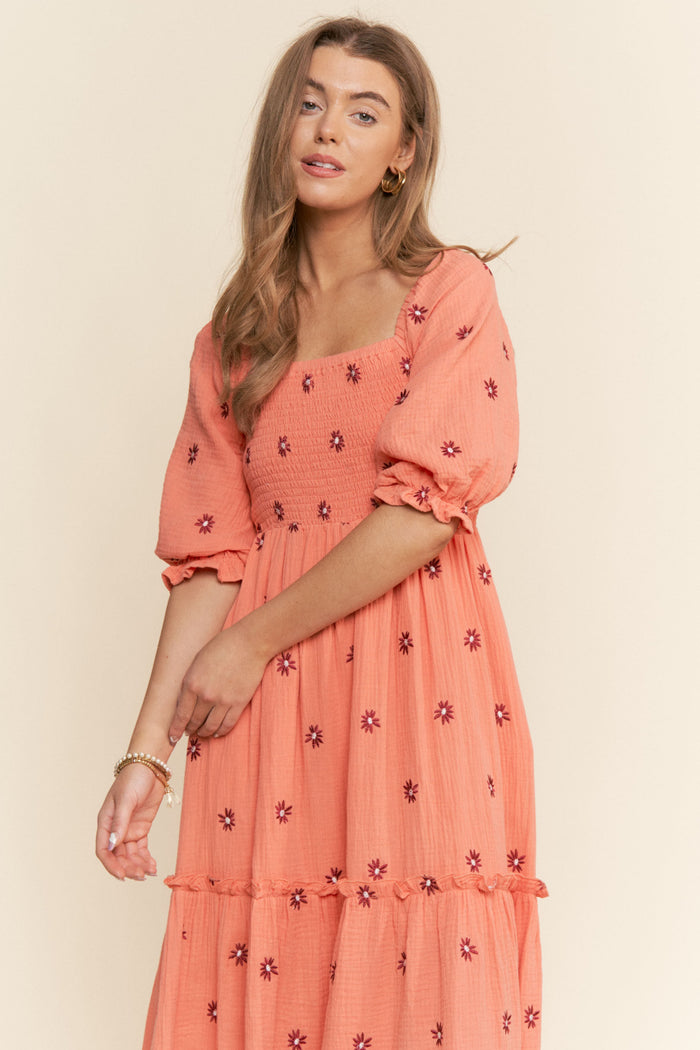 woman wearing an orange floral smocked maxi dress with puff sleeves and ruffle hem